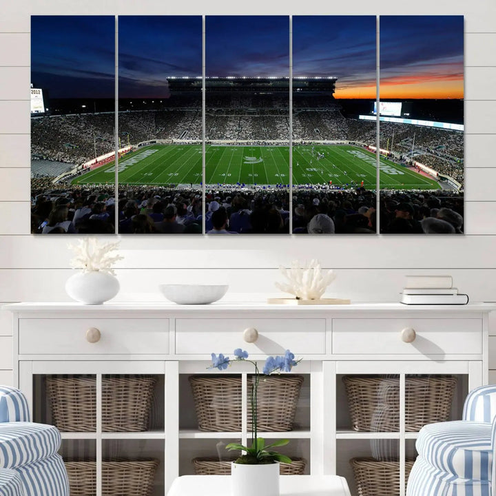 The room showcases a triptych wall art featuring the Michigan State Spartans football team at East Lansing Spartan Stadium at dusk, elegantly printed on premium canvas for a gallery-quality finish.