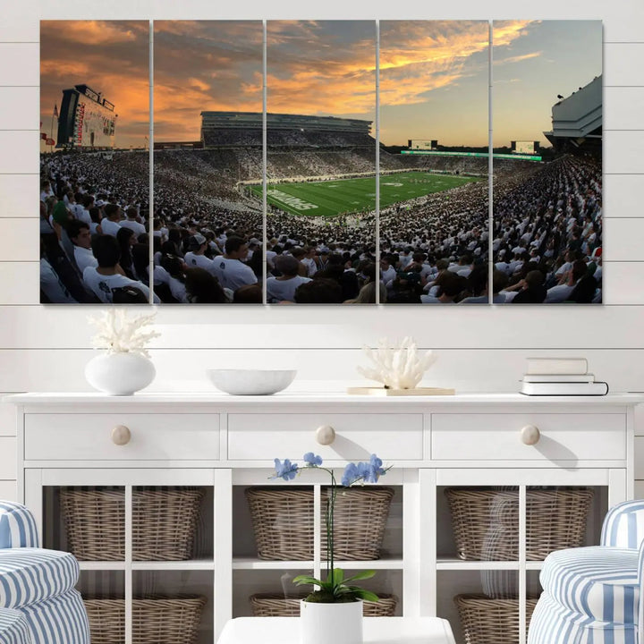 A living room showcasing a stunning Michigan State Spartans Football Team Print on a three-panel canvas, depicting the bustling Spartan Stadium in East Lansing at sunset, all handmade in the USA.