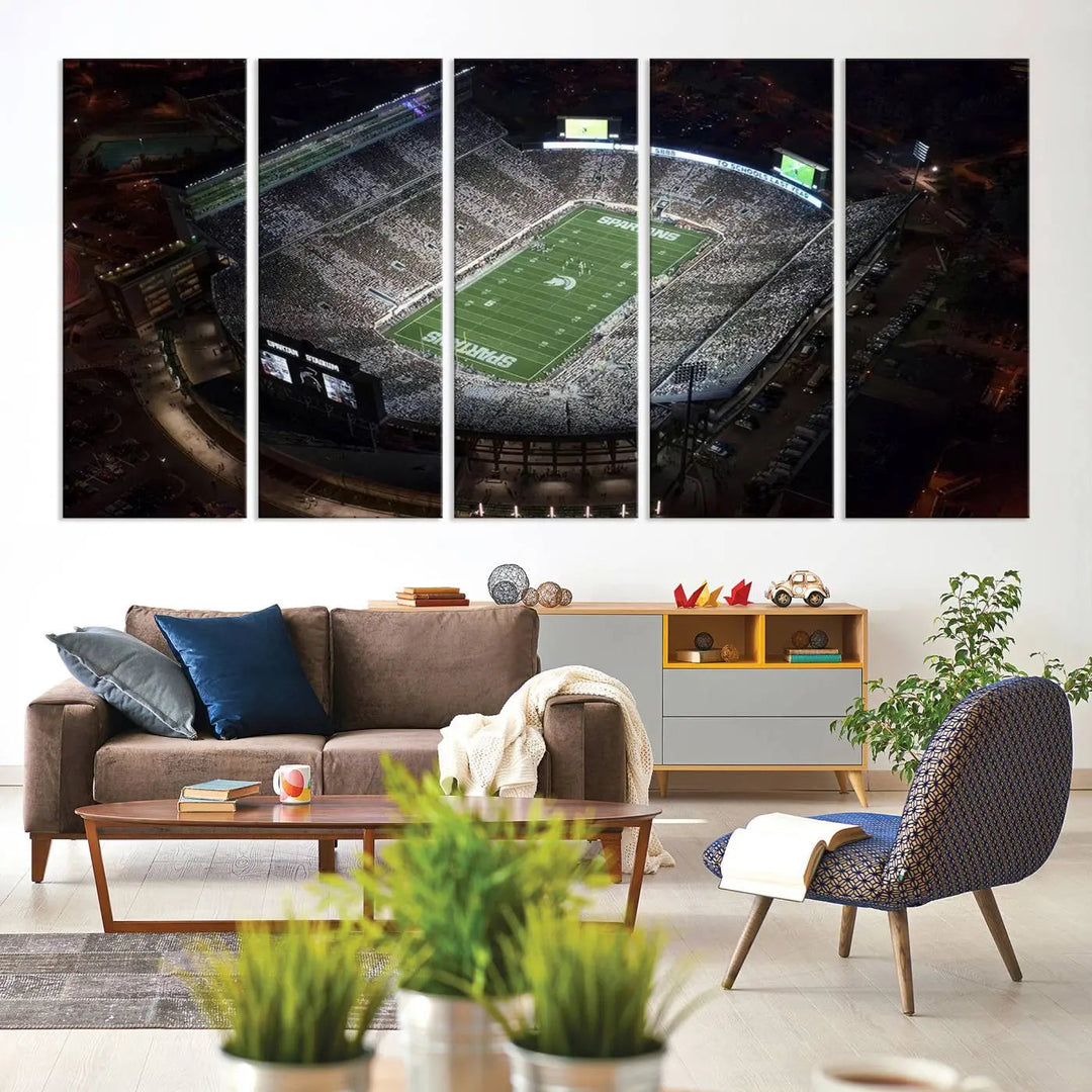 The "Michigan State Spartans Football Team Print - East Lansing Spartan Stadium Wall Art Canvas Print" is elegantly displayed on a wall, showcasing a brightly lit football stadium at night with a gallery-quality finish.