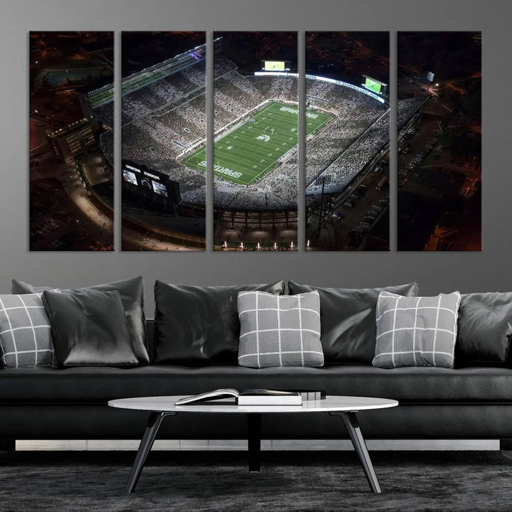 The "Michigan State Spartans Football Team Print - East Lansing Spartan Stadium Wall Art Canvas Print" is elegantly displayed on a wall, showcasing a brightly lit football stadium at night with a gallery-quality finish.