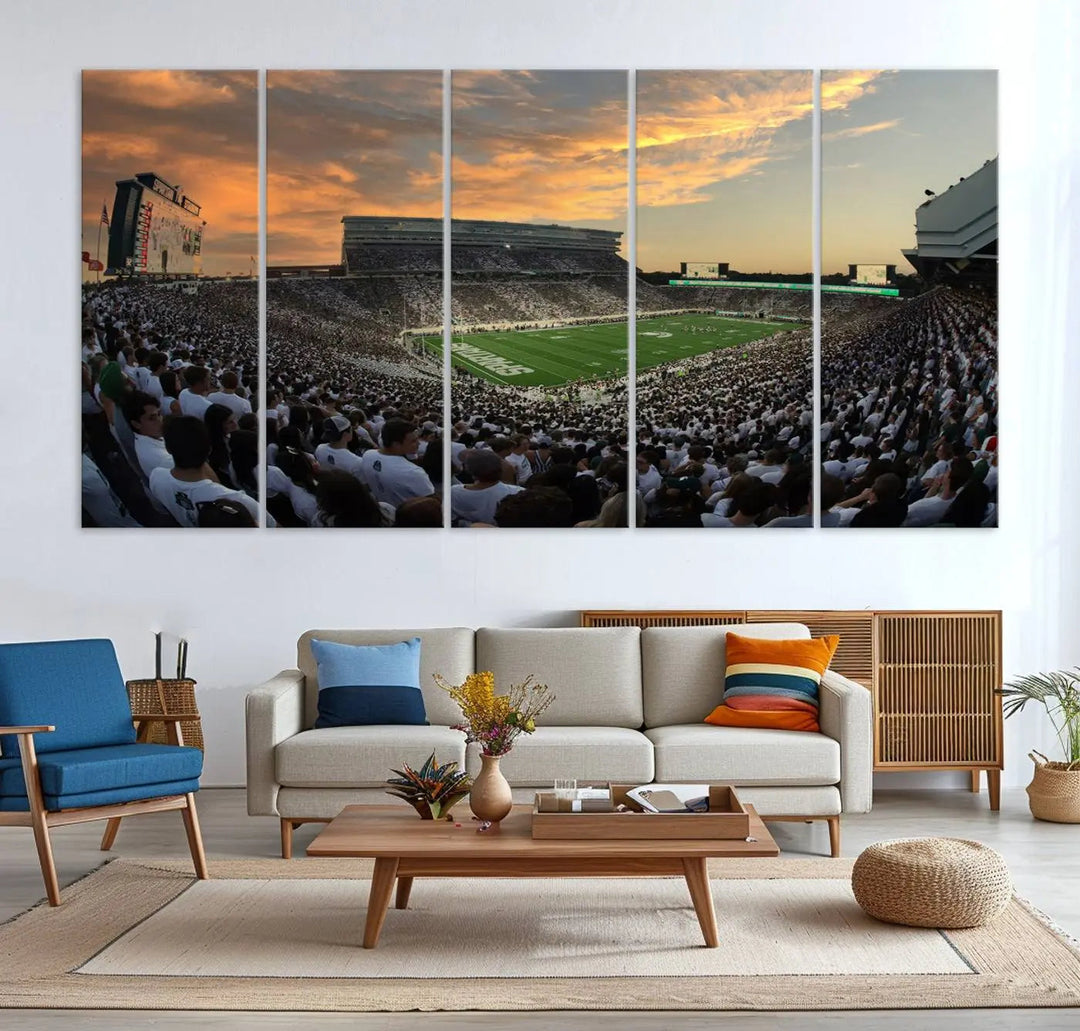 A living room showcasing a stunning Michigan State Spartans Football Team Print on a three-panel canvas, depicting the bustling Spartan Stadium in East Lansing at sunset, all handmade in the USA.