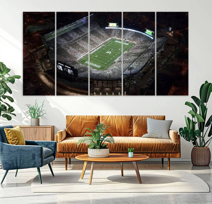 The "Michigan State Spartans Football Team Print - East Lansing Spartan Stadium Wall Art Canvas Print" is elegantly displayed on a wall, showcasing a brightly lit football stadium at night with a gallery-quality finish.