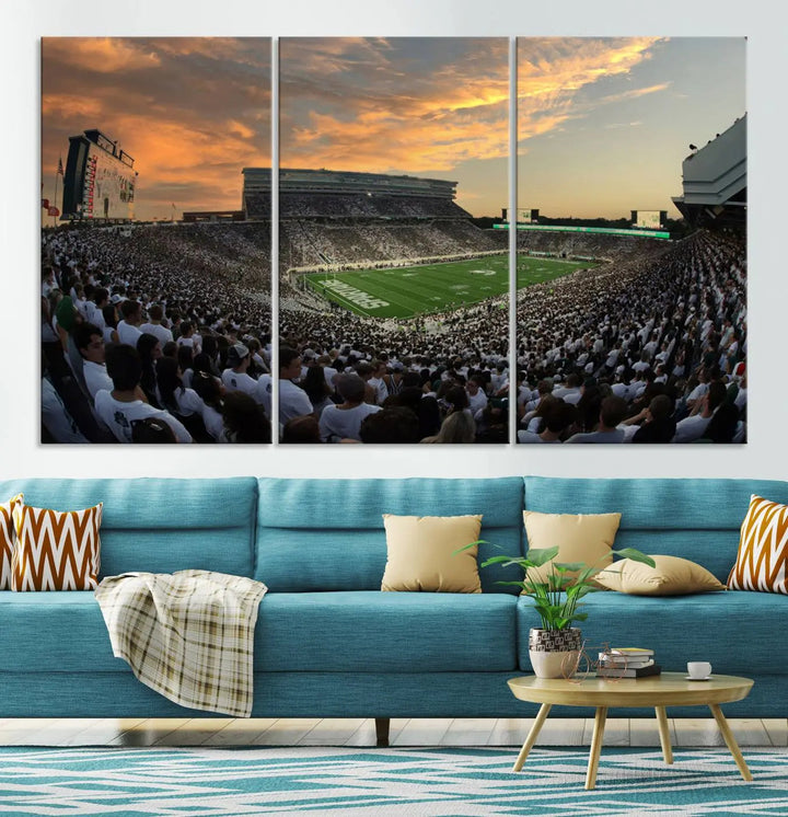 A living room showcasing a stunning Michigan State Spartans Football Team Print on a three-panel canvas, depicting the bustling Spartan Stadium in East Lansing at sunset, all handmade in the USA.