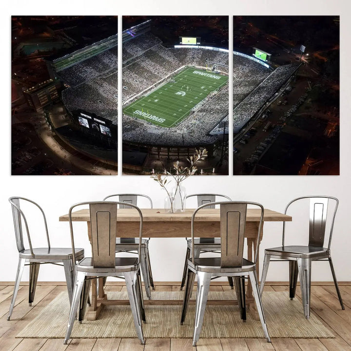 The "Michigan State Spartans Football Team Print - East Lansing Spartan Stadium Wall Art Canvas Print" is elegantly displayed on a wall, showcasing a brightly lit football stadium at night with a gallery-quality finish.