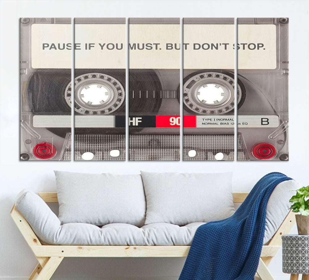 The Music Cassette Iconic Wall Art Canvas Print features a cassette tape with the inspiring message "Pause if you must. But don't stop." It is elegantly printed on museum-quality canvas with a UV-protective coating to ensure long-lasting vibrancy. This gallery-wrapped piece is perfect for any modern space.