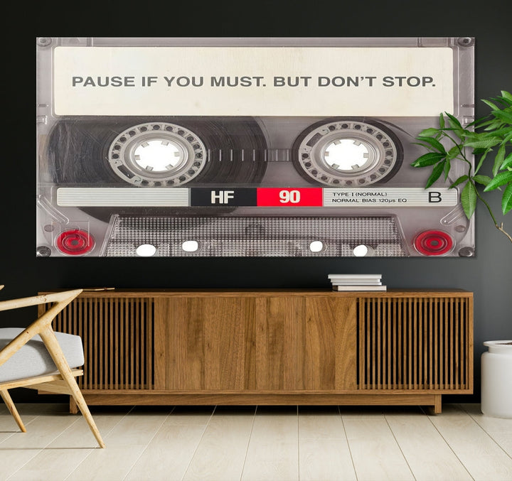 The Music Cassette Iconic Wall Art Canvas Print features a cassette tape with the inspiring message "Pause if you must. But don't stop." It is elegantly printed on museum-quality canvas with a UV-protective coating to ensure long-lasting vibrancy. This gallery-wrapped piece is perfect for any modern space.