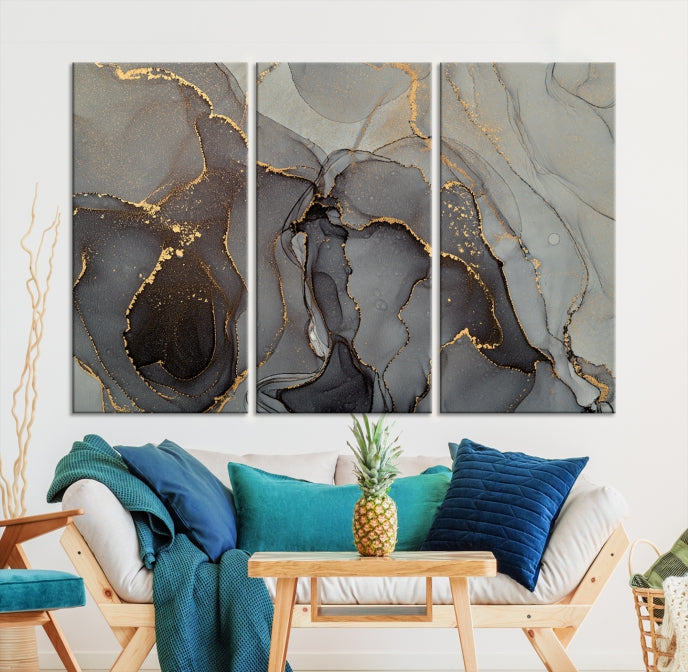 The Gray Marble Fluid Effect Wall Art Abstract Canvas Wall Art Print is a museum-quality canvas featuring triptych abstract art with swirling gray and gold patterns. Complete with a UV-protective coating, this piece of artwork arrives ready to hang, effortlessly elevating your living space.