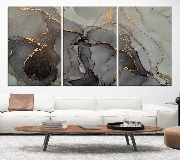 The Gray Marble Fluid Effect Wall Art Abstract Canvas Wall Art Print is a museum-quality canvas featuring triptych abstract art with swirling gray and gold patterns. Complete with a UV-protective coating, this piece of artwork arrives ready to hang, effortlessly elevating your living space.