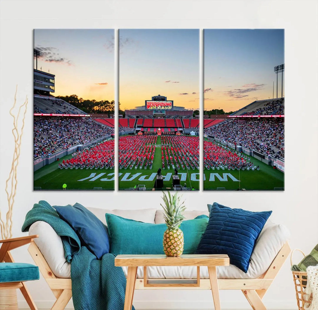 The wall art in the living room features the NC State Wolfpack Football Team Print, beautifully depicting Raleigh's Carter-Finley Stadium at sunset with a crowd dressed in red uniforms. Its gallery-quality finish on premium canvas transforms the scene into captivating artwork.