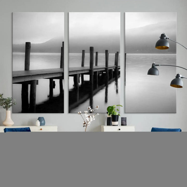 The "Ocean Beach Canvas Wall Art" is a black-and-white triptych depicting a serene dock over water.