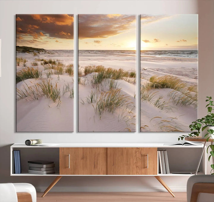 A triptych of the Ocean Beach Wall Art Canvas Print Sunset Artwork Print Coastal Wall Art showcases a serene beach landscape with sand dunes and grasses, gallery wrapped on museum-quality canvas.