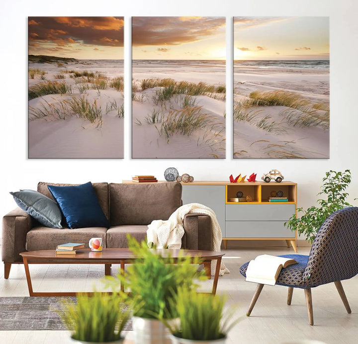 A triptych of the Ocean Beach Wall Art Canvas Print Sunset Artwork Print Coastal Wall Art showcases a serene beach landscape with sand dunes and grasses, gallery wrapped on museum-quality canvas.