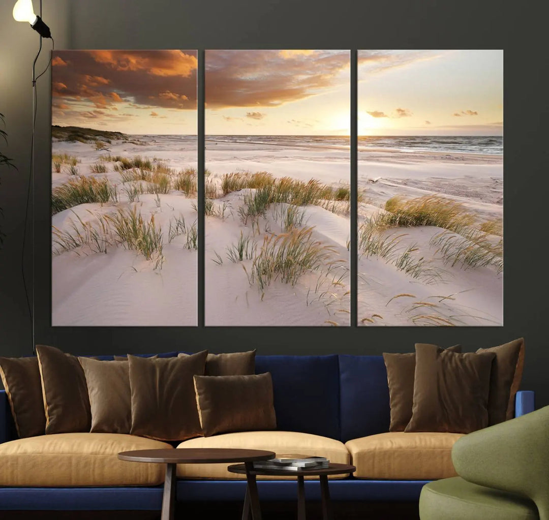 A triptych of the Ocean Beach Wall Art Canvas Print Sunset Artwork Print Coastal Wall Art showcases a serene beach landscape with sand dunes and grasses, gallery wrapped on museum-quality canvas.