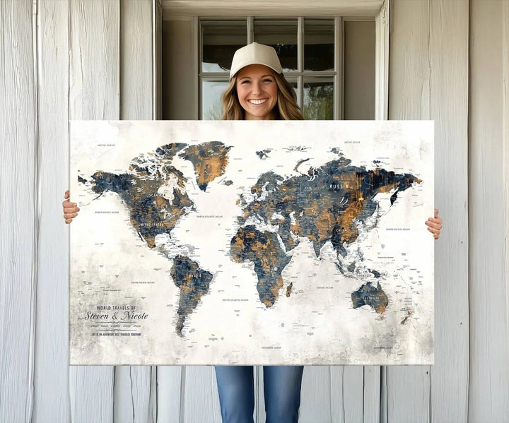 A smiling woman proudly holds the Personalized Push Pin Map Wall Art Print - Detailed Custom World Map Canvas Print in front of a white wall, perfect for travel enthusiasts eager to mark their adventures.