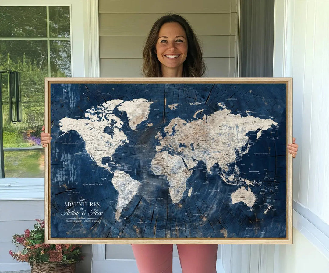 A woman smiles while holding a Personalized World Map Wall Art Print, featuring a custom design with a blue background, elegantly framed.