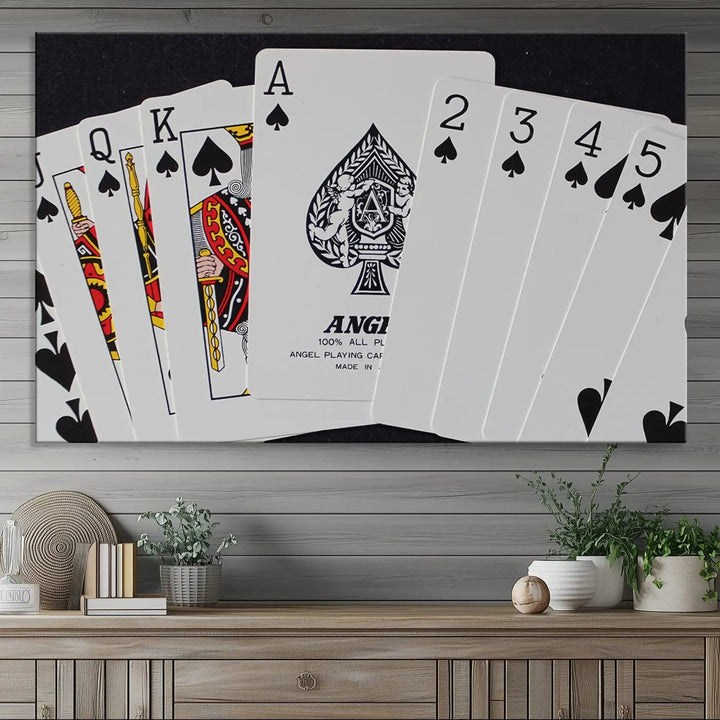 The Poker Wall Art - Playing Cards Canvas Wall Art Print features an Ace of Spades and Royal Flush design. This piece adds a classic charm to any space with its subtle emphasis on the Ace of Spades, making it perfect for game room decor.