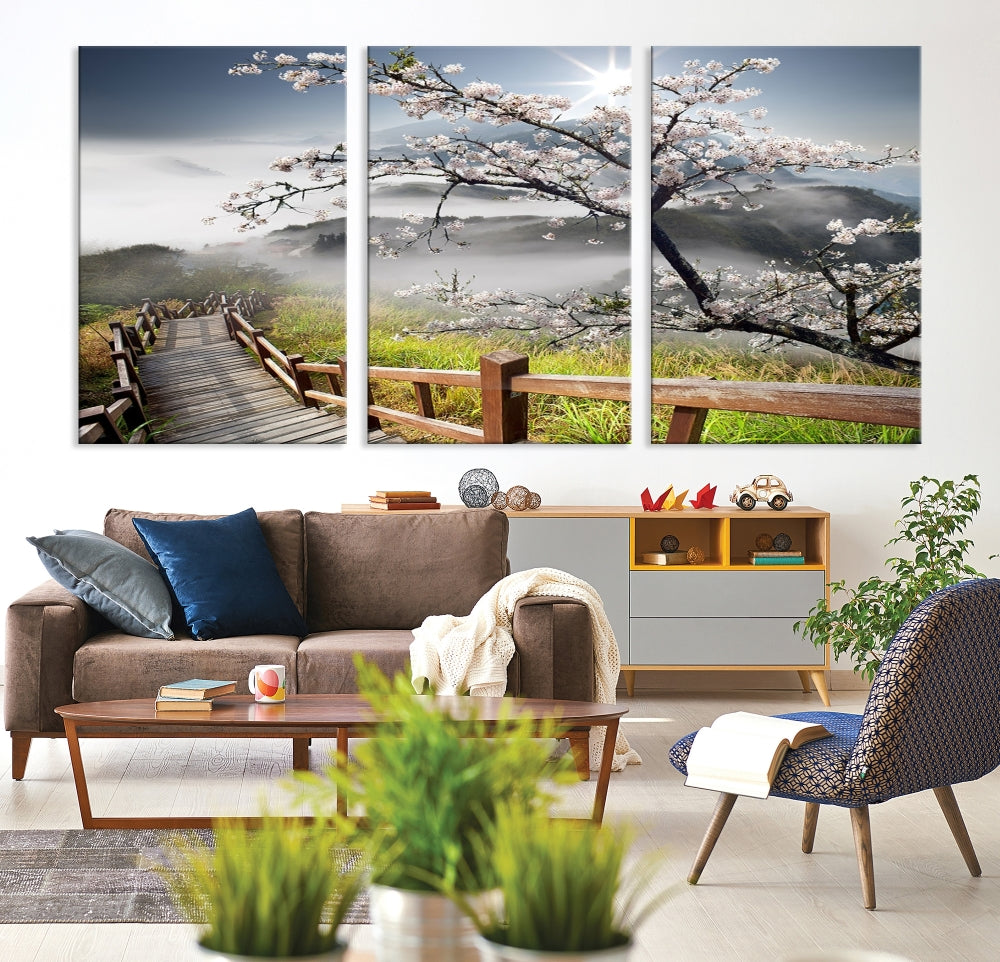 Canvas wall art featuring a scenic wooden walkway surrounded by cherry blossoms and misty mountains, ready to hang.