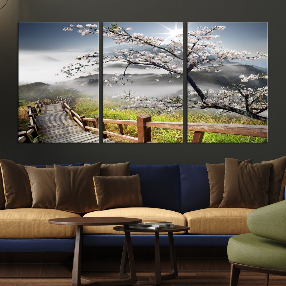 Canvas wall art featuring a scenic wooden walkway surrounded by cherry blossoms and misty mountains, ready to hang.