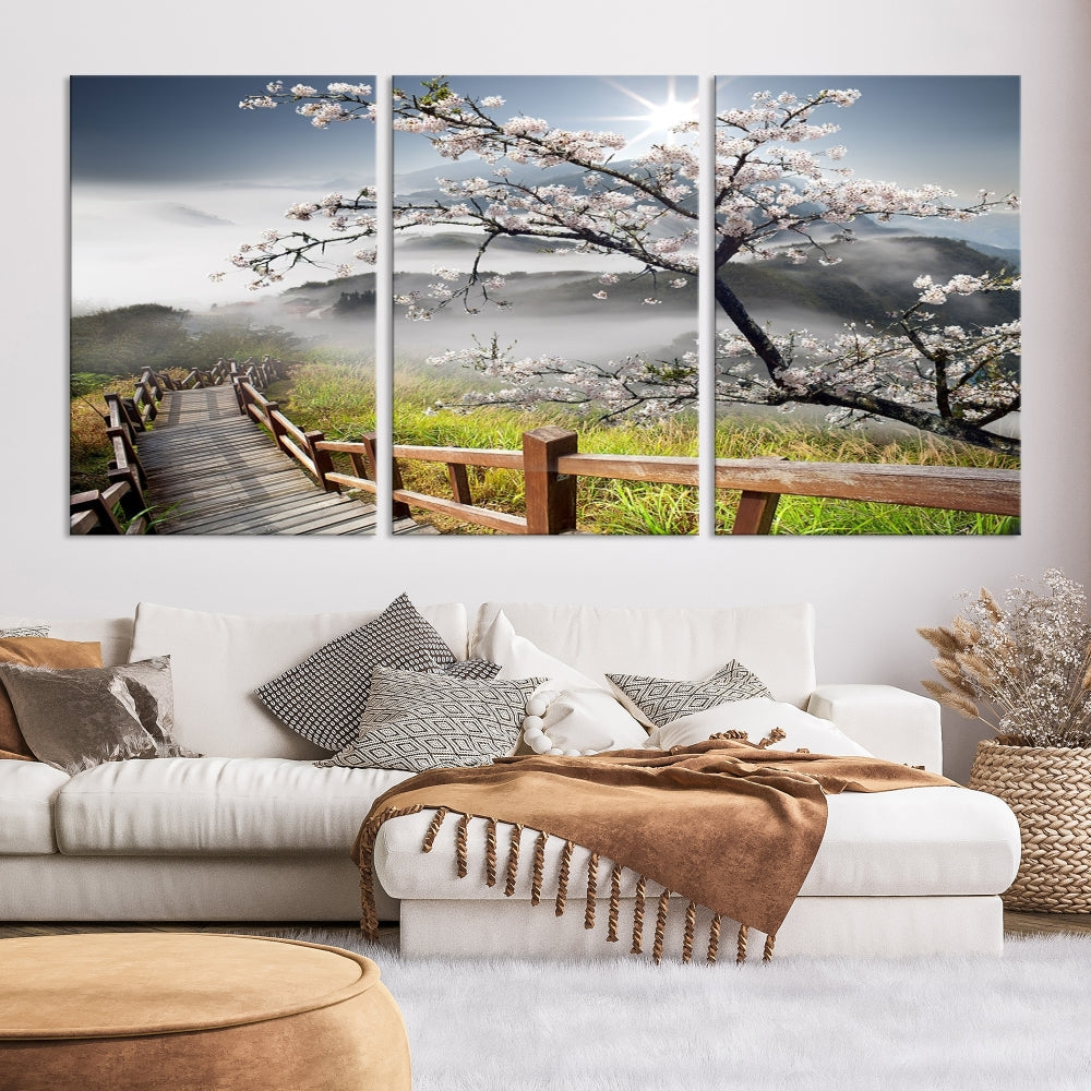 Canvas wall art featuring a scenic wooden walkway surrounded by cherry blossoms and misty mountains, ready to hang.