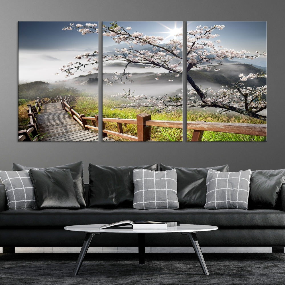 Canvas wall art featuring a scenic wooden walkway surrounded by cherry blossoms and misty mountains, ready to hang.