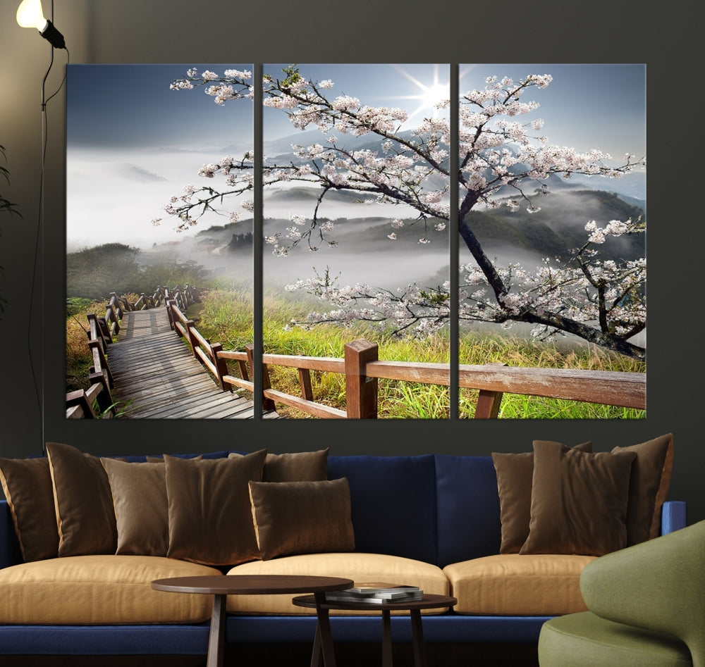 Canvas wall art featuring a scenic wooden walkway surrounded by cherry blossoms and misty mountains, ready to hang.