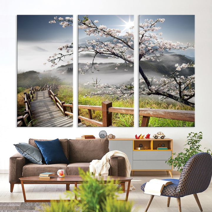 Canvas wall art featuring a scenic wooden walkway surrounded by cherry blossoms and misty mountains, ready to hang.