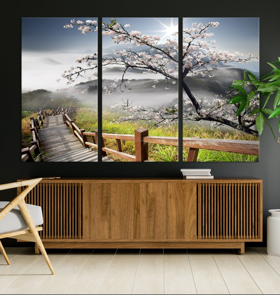 Canvas wall art featuring a scenic wooden walkway surrounded by cherry blossoms and misty mountains, ready to hang.