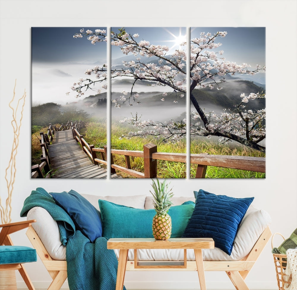 Canvas wall art featuring a scenic wooden walkway surrounded by cherry blossoms and misty mountains, ready to hang.