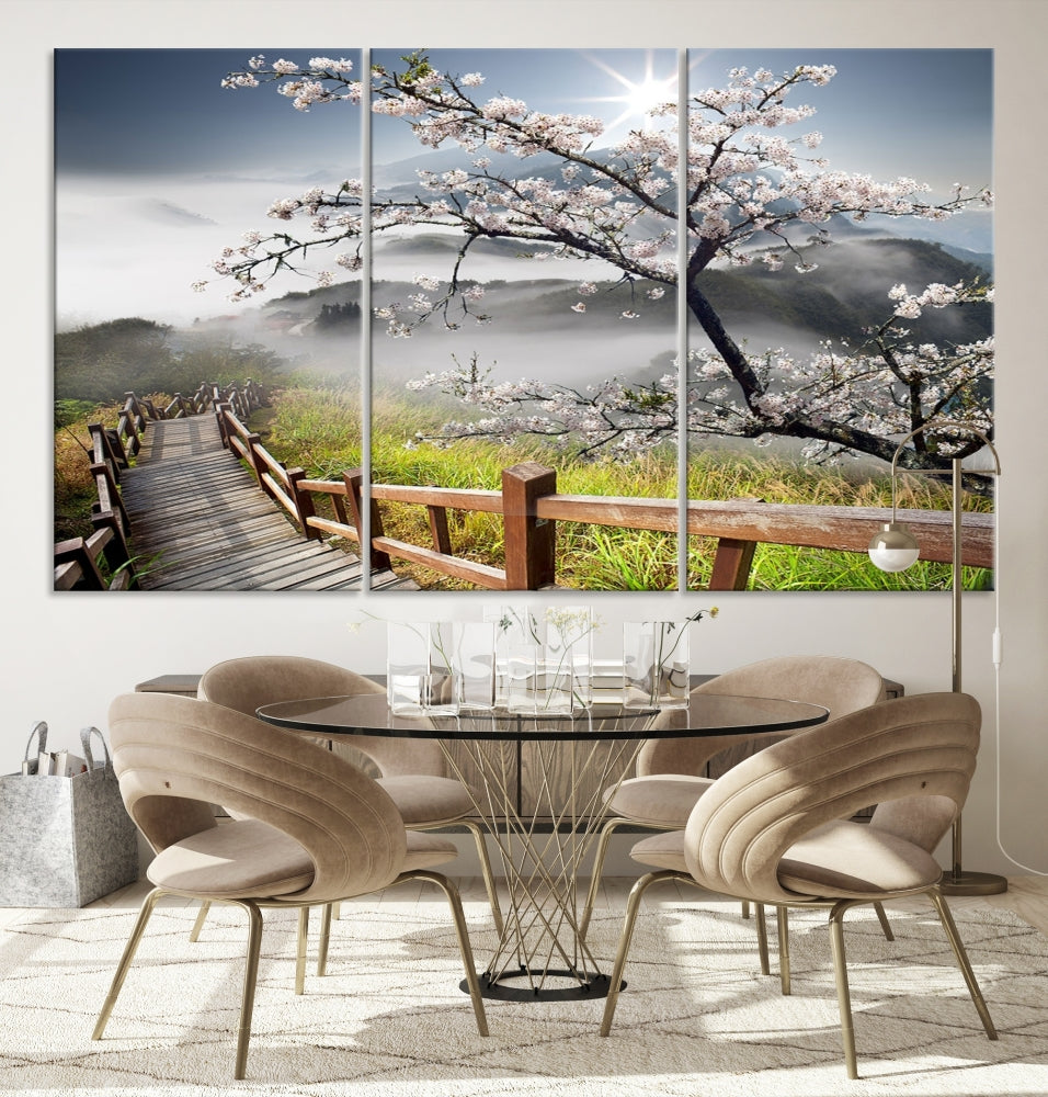 Canvas wall art featuring a scenic wooden walkway surrounded by cherry blossoms and misty mountains, ready to hang.