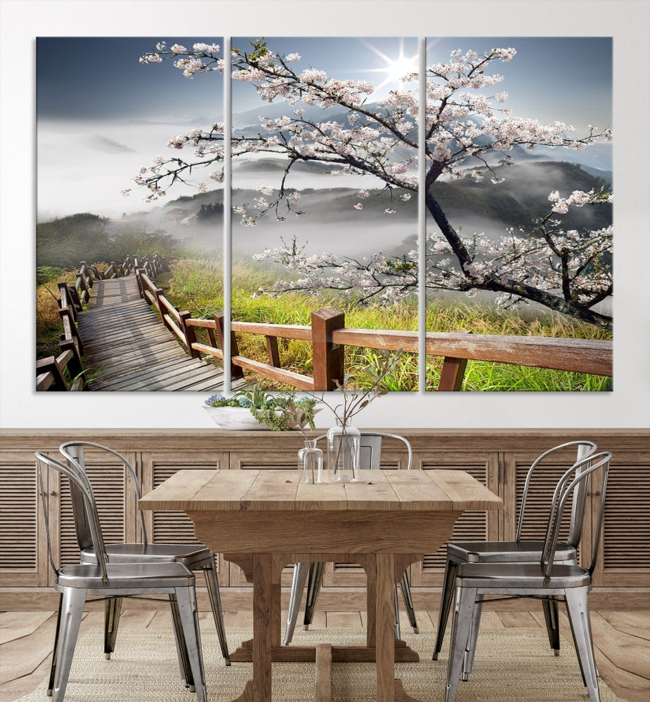 Canvas wall art featuring a scenic wooden walkway surrounded by cherry blossoms and misty mountains, ready to hang.