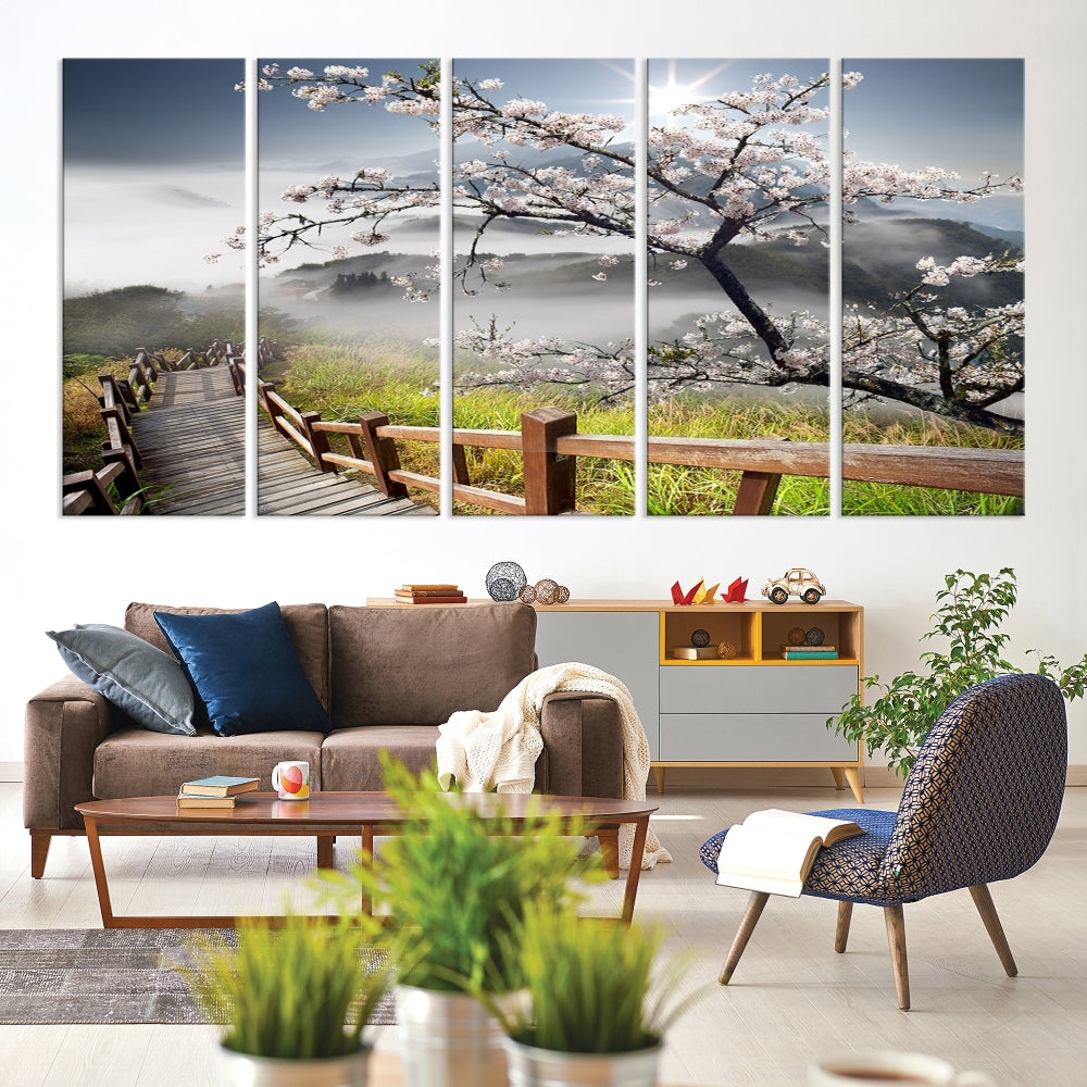 Canvas wall art featuring a scenic wooden walkway surrounded by cherry blossoms and misty mountains, ready to hang.