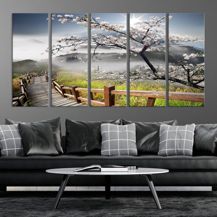 Canvas wall art featuring a scenic wooden walkway surrounded by cherry blossoms and misty mountains, ready to hang.