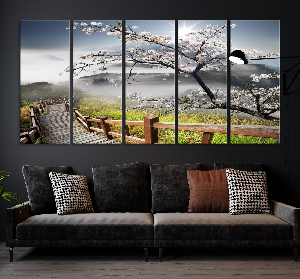 Canvas wall art featuring a scenic wooden walkway surrounded by cherry blossoms and misty mountains, ready to hang.