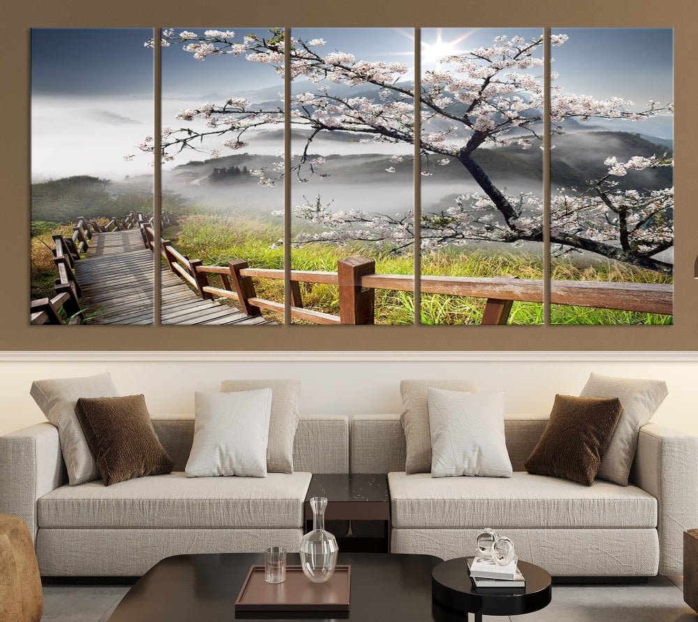 Canvas wall art featuring a scenic wooden walkway surrounded by cherry blossoms and misty mountains, ready to hang.