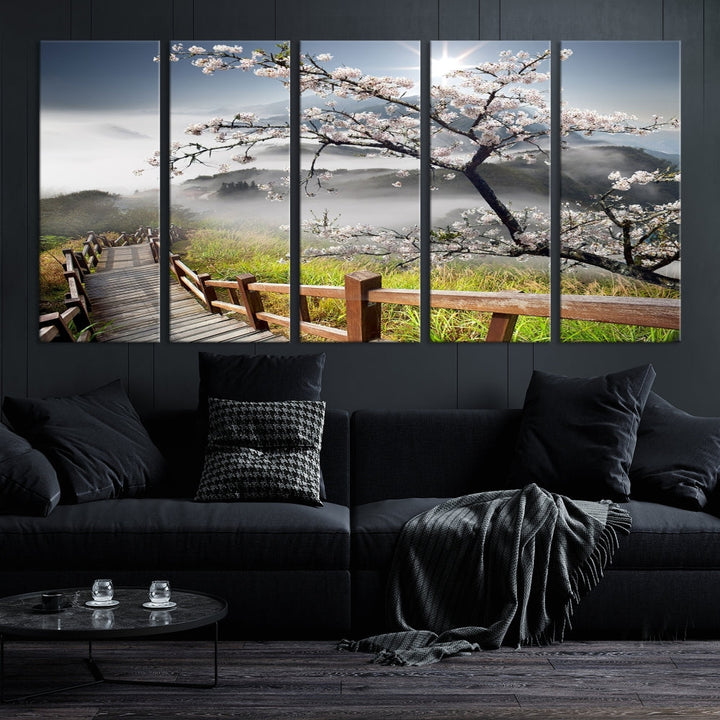 Canvas wall art featuring a scenic wooden walkway surrounded by cherry blossoms and misty mountains, ready to hang.