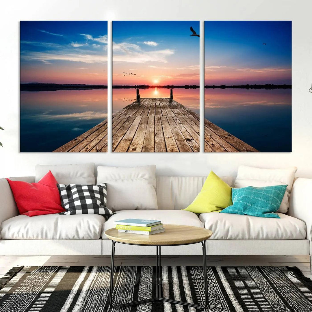 A Sea Wooden Pier Canvas Wall Art, featuring a sunset artwork print of the beach, fosters a coastal ambiance in the modern living room.