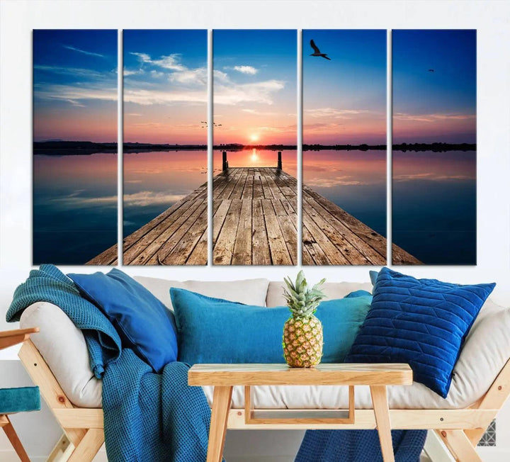 A Sea Wooden Pier Canvas Wall Art, featuring a sunset artwork print of the beach, fosters a coastal ambiance in the modern living room.