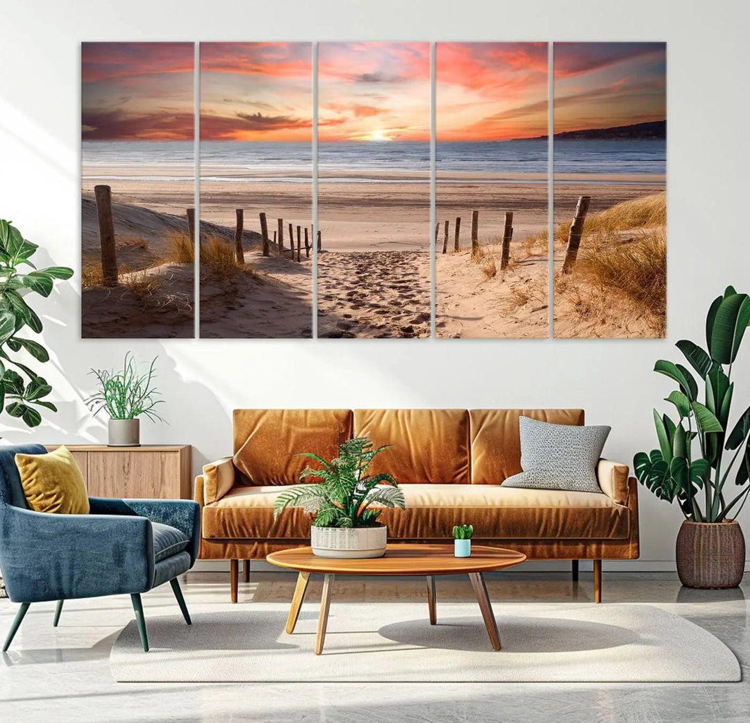 A Giclee Print on Canvas featuring the Serene Beach Path Sunset, showcased as a Vibrant Sunset Triptych and Coastal Sand Dunes Wall Art, is displayed on a modern wooden wall.