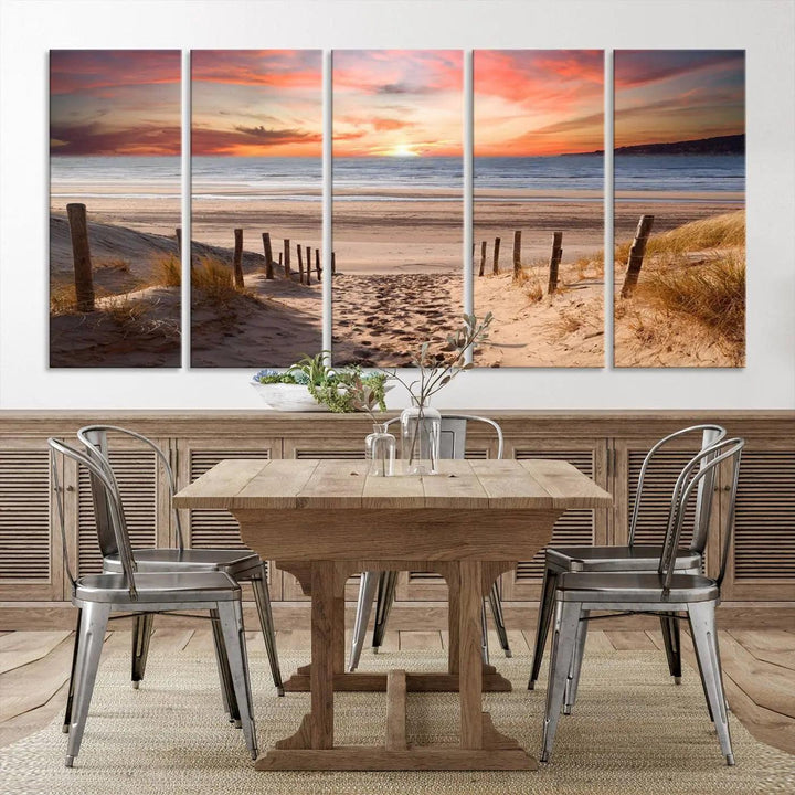 A Giclee Print on Canvas featuring the Serene Beach Path Sunset, showcased as a Vibrant Sunset Triptych and Coastal Sand Dunes Wall Art, is displayed on a modern wooden wall.