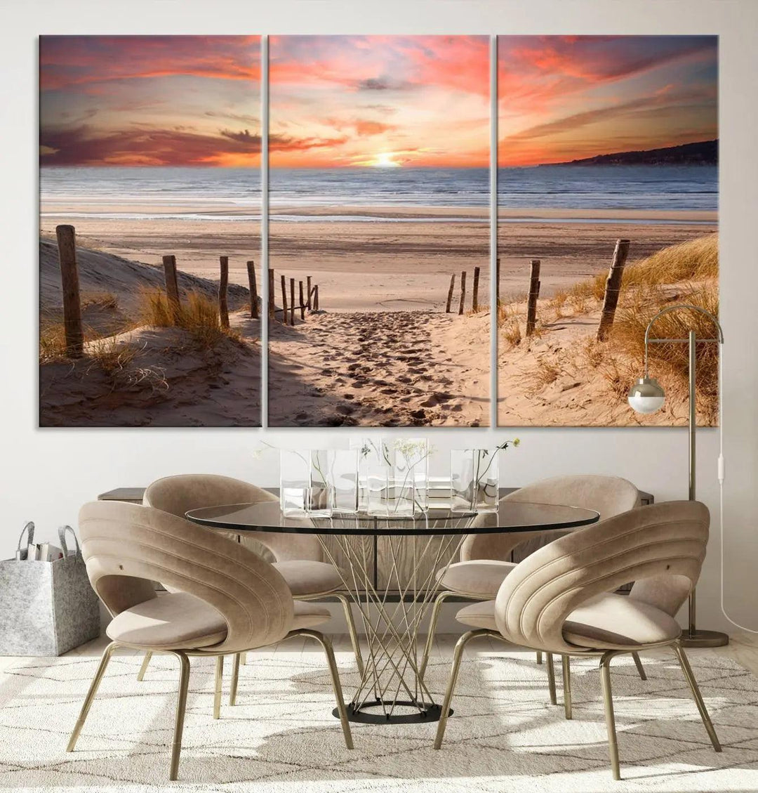 A Giclee Print on Canvas featuring the Serene Beach Path Sunset, showcased as a Vibrant Sunset Triptych and Coastal Sand Dunes Wall Art, is displayed on a modern wooden wall.