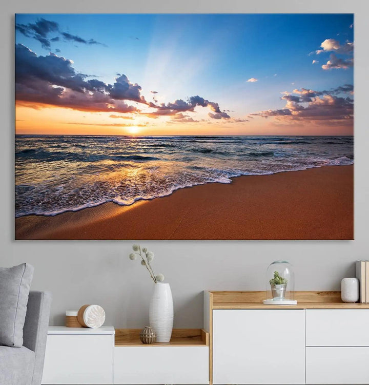 The "Serene Ocean Sunset Canvas Print, Golden Hour Beach Wall Art" offers a captivating view from a sandy beach, where sunlight reflects on the water amidst clouds in a blue sky. This piece, created with Giclee canvas and gallery wrap featuring Canon print quality, brings tranquility and an ideal enhancement to coastal interiors.