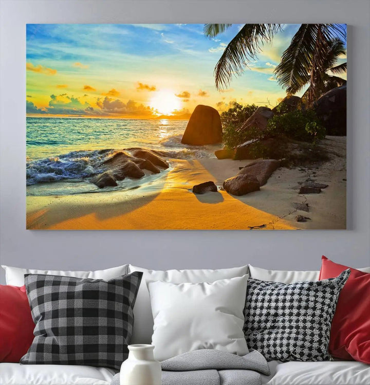 The Serene Tropical Beach Sunset Canvas Wall Art, a 3-panel giclee print, beautifully captures an ocean sunset with its depiction of palm trees and a coastal rock formation.