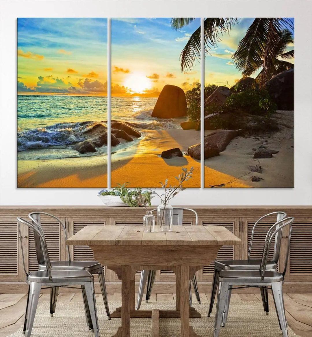 The Serene Tropical Beach Sunset Canvas Wall Art, a 3-panel giclee print, beautifully captures an ocean sunset with its depiction of palm trees and a coastal rock formation.