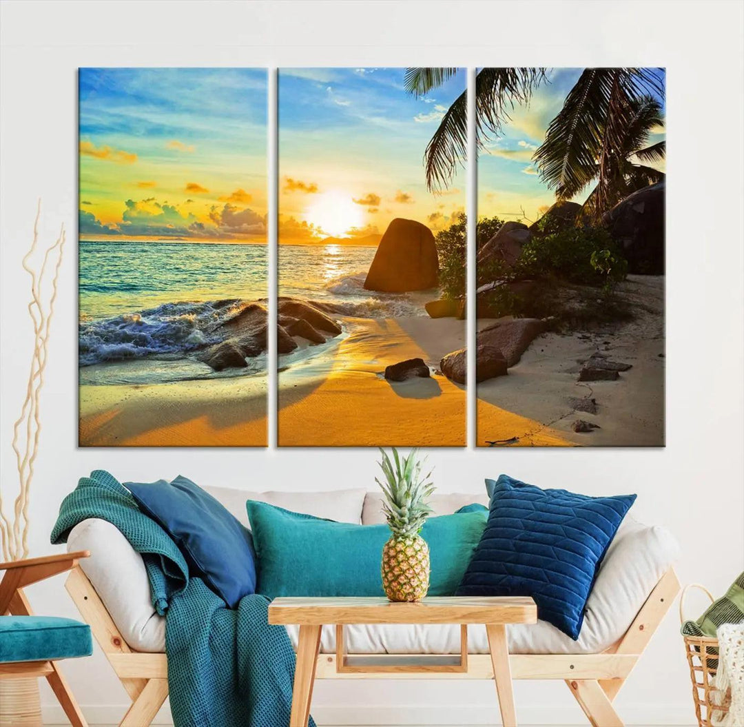 The Serene Tropical Beach Sunset Canvas Wall Art, a 3-panel giclee print, beautifully captures an ocean sunset with its depiction of palm trees and a coastal rock formation.