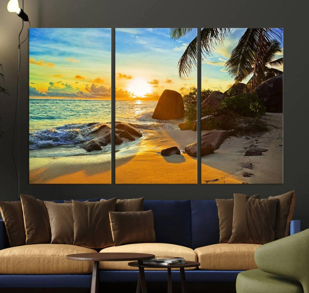 The Serene Tropical Beach Sunset Canvas Wall Art, a 3-panel giclee print, beautifully captures an ocean sunset with its depiction of palm trees and a coastal rock formation.