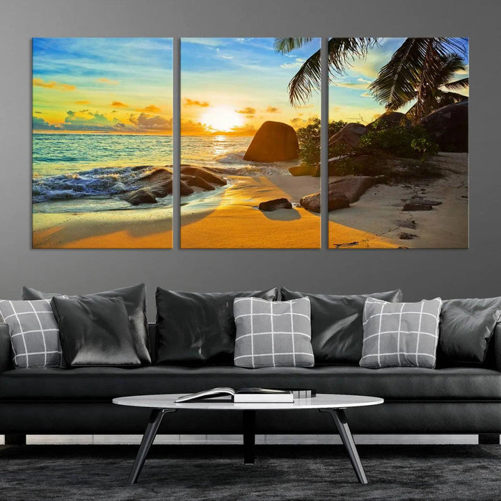 The Serene Tropical Beach Sunset Canvas Wall Art, a 3-panel giclee print, beautifully captures an ocean sunset with its depiction of palm trees and a coastal rock formation.