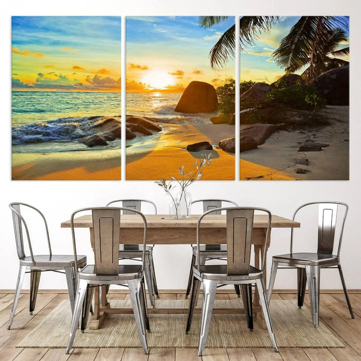 The Serene Tropical Beach Sunset Canvas Wall Art, a 3-panel giclee print, beautifully captures an ocean sunset with its depiction of palm trees and a coastal rock formation.