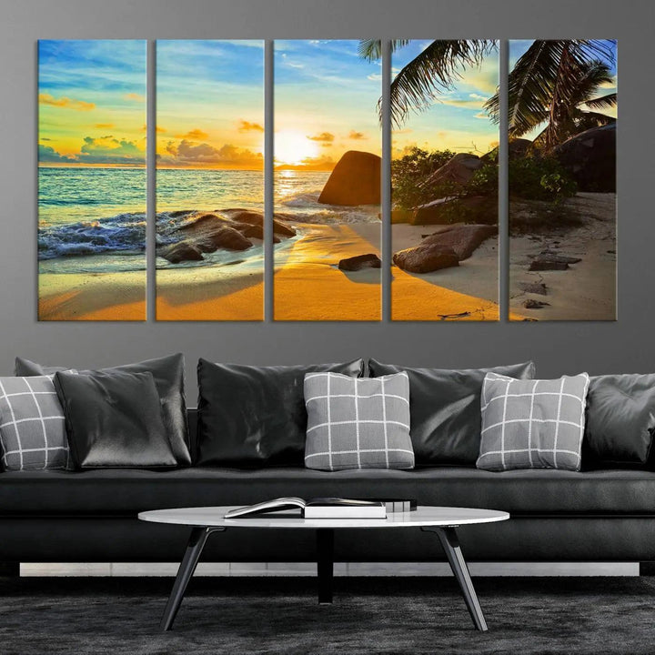 The Serene Tropical Beach Sunset Canvas Wall Art, a 3-panel giclee print, beautifully captures an ocean sunset with its depiction of palm trees and a coastal rock formation.