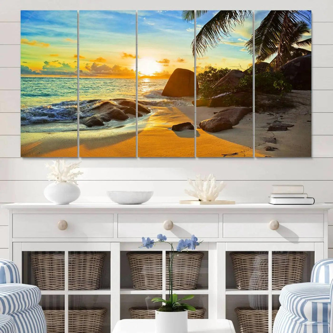 The Serene Tropical Beach Sunset Canvas Wall Art, a 3-panel giclee print, beautifully captures an ocean sunset with its depiction of palm trees and a coastal rock formation.