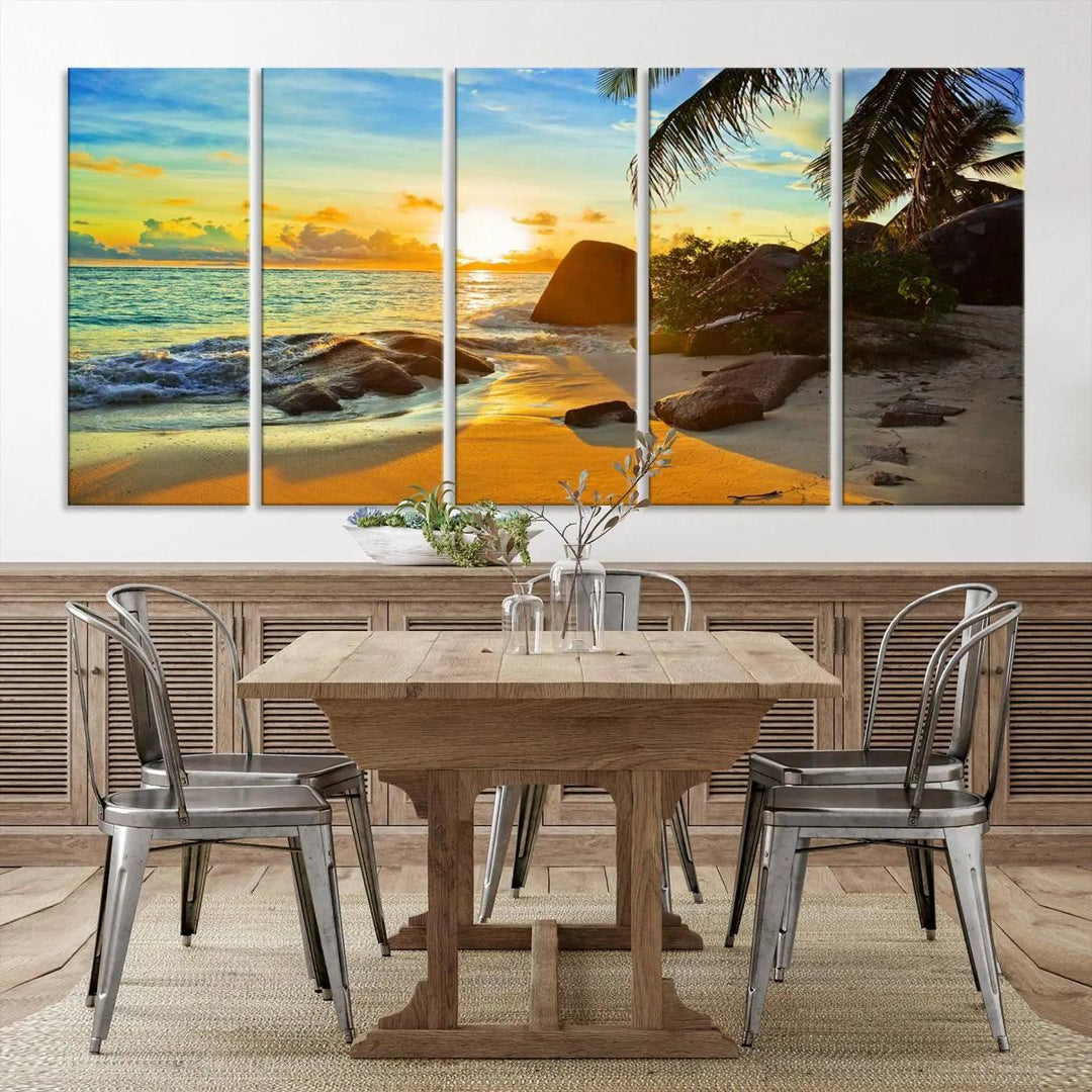 The Serene Tropical Beach Sunset Canvas Wall Art, a 3-panel giclee print, beautifully captures an ocean sunset with its depiction of palm trees and a coastal rock formation.